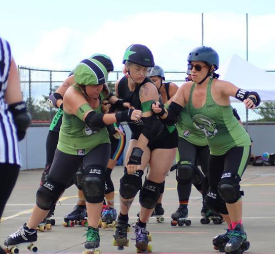 Maui's jammer escaping through a Pacific pack; skaters in black+green and green+black.